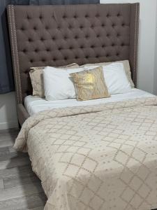 Una cama grande con cabecera acolchada y almohadas. en Luxury Haven by Kc & Flo, en Calgary