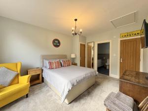 - une chambre avec un lit et une chaise jaune dans l'établissement Flat 2, Waterloo Apartments, à Radstock 3 autres photos