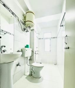 a white bathroom with a toilet and a sink at Hotel Swagat in Pelling