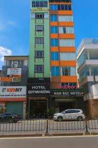a tall building with cars parked in front of it at Quỳnh Hương Hotel Phú Nhuận in Ho Chi Minh City