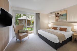 a bedroom with a bed and a tv and a chair at Coral Coast Resort Accor Vacation Club Apartments in Palm Cove