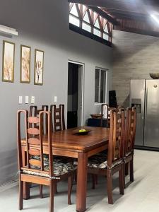 a wooden dining room table with chairs and a refrigerator at Condominium Village V Praia dos Carneiros-PE in Tamandaré