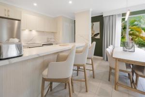 an open kitchen and dining room with white chairs at Coral Coast Resort Accor Vacation Club Apartments in Palm Cove