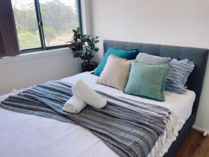 a bed with a blanket and pillows on it at Colebee5 BR house near park and shop in Schofields