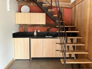 una cucina con mobili in legno e una scala a chiocciola di Gîte rustique au calme avec cheminée et jardin, 4 pers. - FR-1-489-600 a La Faye