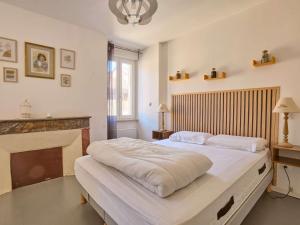 a bedroom with a large white bed and a fireplace at Maison T3 rénovée au cœur de Cazaubon, pour 2 à 4 pers. - FR-1-841-83 in Cazaubon