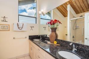 a bathroom with a sink and a vase of flowers at Kahana Village 2 · KHV 2 Direct Oceanfront 2BD Condo Steps to Be in Kahana +42 photos