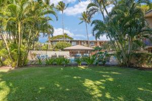 a yard with palm trees and a fence at Kihei Garden Estates G207 · KGE G207 Newly Updated 2BD Condo AC in Kihei