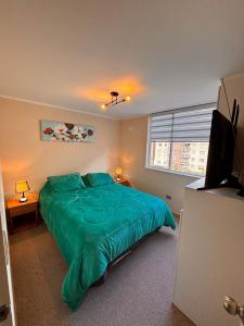een slaapkamer met een groen bed en een flatscreen-tv bij Departamento villarrica para 4 personas in Villarrica