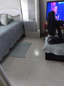 a bedroom with a bed and a tv with a man on it at Pousada Duda Lins in São Vicente