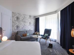 a hotel room with a bed and a chair and a couch at Mercure Aix-les-Bains Domaine de Marlioz Hôtel & Spa in Aix-les-Bains +146 photos