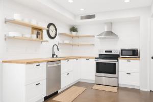 a kitchen with white cabinets and a clock on the wall at OldTown, Splash Pad & Park, Camelback Mountain trails, Desert Chic Retreat in Scottsdale