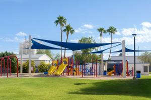a playground with a blue canopy and slides in a park at OldTown, Splash Pad & Park, Camelback Mountain trails, Desert Chic Retreat in Scottsdale