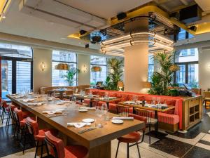 un restaurant avec de longues tables, des chaises et des fenêtres dans l'établissement Pullman Budapest, à Budapest