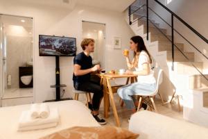 a man and woman sitting at a table in a living room at Shinjuku iotele-hatsudai House in Tokyo