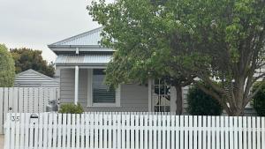 a white fence in front of a house at Pear Tree Cottage in Apollo Bay +4 photos