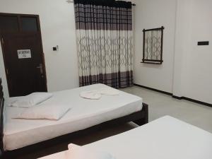 a room with two beds and a door with a window at Yala Thaman in Kataragama