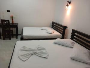 a pair of beds with a bow tie on them at Yala Thaman Katharagama in Kataragama