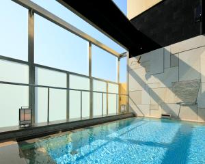 a swimming pool in a building with windows at Candeo Hotels Kobe Tor Road in Kobe