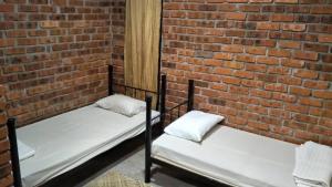 two beds in front of a brick wall at Rareheart Guesthouse in Kuala Terengganu +17 photos