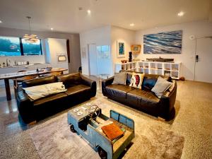 a living room with two leather couches and a table at Luxury Waterfront Marina Apartment - Bay of Islands, New Zealand in Opua +21 photos