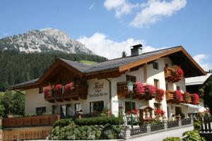 a large building with flowers in front of a mountain at Haus Jäger in Filzmoos