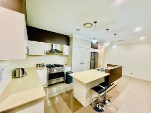 a kitchen with white cabinets and a stove top oven at Entire 4 Bed Rooms Sanctuary in West Hoxton +34 photos