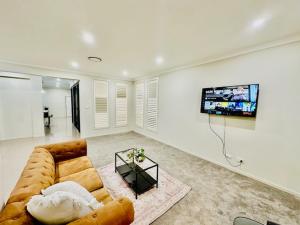 a living room with a couch and a flat screen tv at Entire 4 Bed Rooms Sanctuary in West Hoxton