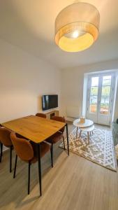 une salle à manger avec une table, des chaises et une télévision dans l'établissement Le Terra Redon - T2 tout équipé avec balcon, local vélo et gare à 6 minutes à pied, à Redon
