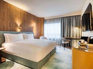 a hotel room with a large bed and a desk at Mövenpick hotel Brussels airport in Zaventem +95 photos