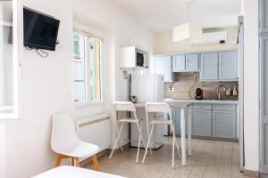a kitchen with white cabinets and white stools at MARNE - Cosy studio in Menton in Menton
