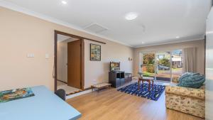 a living room with a table and a couch at Gwendolen Cottage - Umina Beach in Ettalong Beach