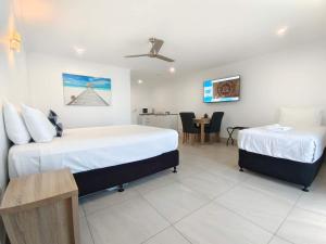 a hotel room with two beds and a table at Best Western Ambassador Motor Lodge in Hervey Bay