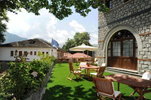 a patio with a table and chairs on a lawn at Hotel Adonis in Metsovo