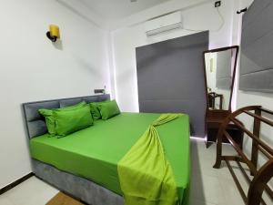 a green bed in a room with a mirror at Sithujaya Green Mirissa in Mirissa