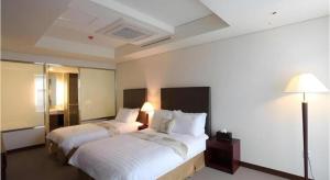 a hotel room with two beds and a lamp at Hotel Sunshine in Daejeon