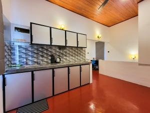 a kitchen with white cabinets and a wooden ceiling at Sithujaya Green Mirissa in Mirissa
