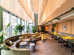 Un vestíbulo con sofás, mesas y ventanas. en TRIBE Düsseldorf, en Düsseldorf