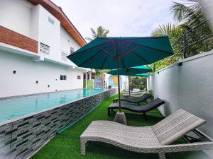a patio with two chairs and an umbrella next to a swimming pool at Sithujaya Green Mirissa in Mirissa