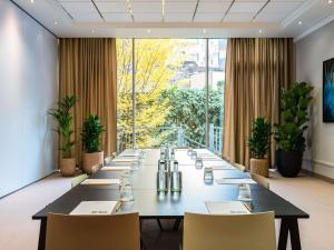 Una gran sala de conferencias con una mesa larga y sillas. en TRIBE Düsseldorf, en Düsseldorf