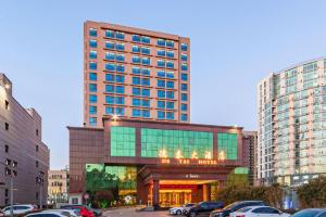 Un gran edificio con coches aparcados delante. en Qingdao Chengyang Detai Hotel, en Qingdao