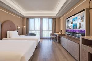 a hotel room with two beds and a flat screen tv at Mercure Xi'an Chanba in Xi'an