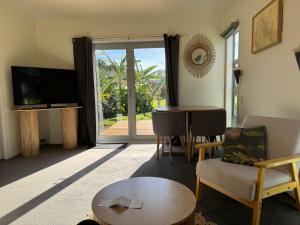 a living room with a tv and a couch and a table at Wheatstone Hideaway in Gisborne