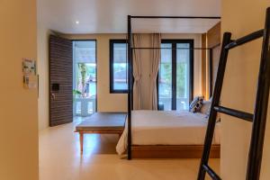 a bedroom with a bed and a bench and windows at The Anda Mani Khaolak Beachfront Villas in Khao Lak +100 photos