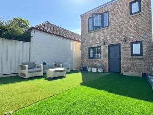 een tuin met twee stoelen en een huis bij Trendy 4BR Petersham Stay Steps from Top Cafés in Sydney