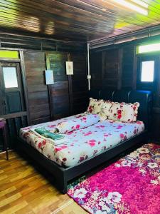 Cama en habitación con alfombra rosa en Rumah Kayu Homestay, en Bedung