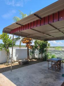un pabellón con una mesa y sillas debajo en Rumah Kayu Homestay, en Bedung