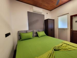 a bedroom with a green bed with two green pillows at Sithujaya Green Mirissa in Mirissa