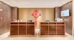 Un vestíbulo con dos escritorios de madera y una sombrilla roja. en Jinjiang Metropolo Zhengzhou Songshan Road, en Zhengzhou