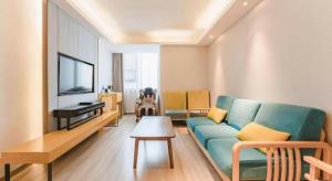 Una sala de estar con un sofá azul y un televisor de pantalla plana. en Jinjiang Metropolo Zhengzhou Songshan Road, en Zhengzhou